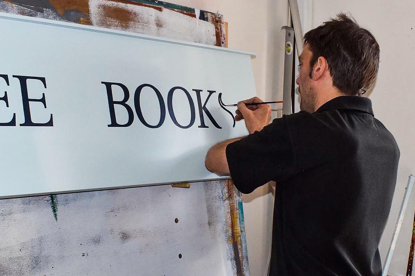 Signwriter hand lettering The Beehive's sign in 2021